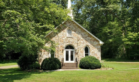Stone church surrounded by leafy trees